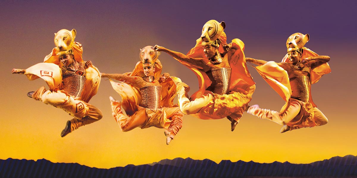 Two lionesses leap gracefully against a vibrant sunset backdrop, showcasing their powerful bodies and dynamic movement.