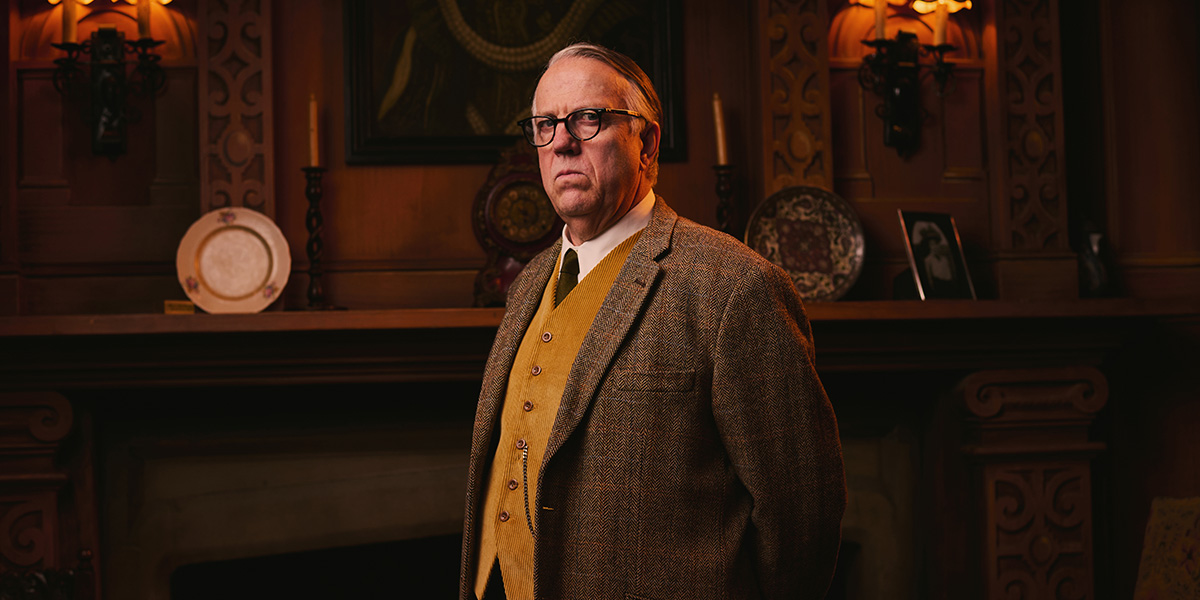 A scene from "The Mousetrap" featuring a character in period costume, with a wooden stage backdrop.