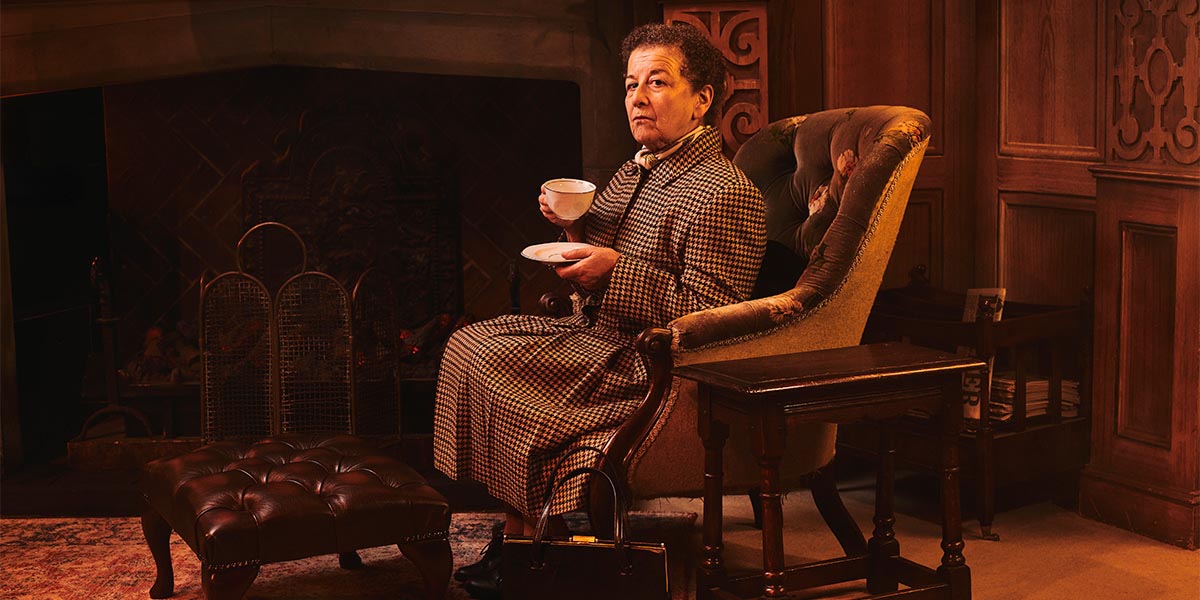 A stage scene from "The Mousetrap" featuring actors in period costumes, with dramatic lighting and set design.
