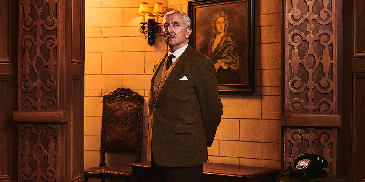 A scene from "The Mousetrap" featuring actors in period costumes on stage, with dramatic lighting.