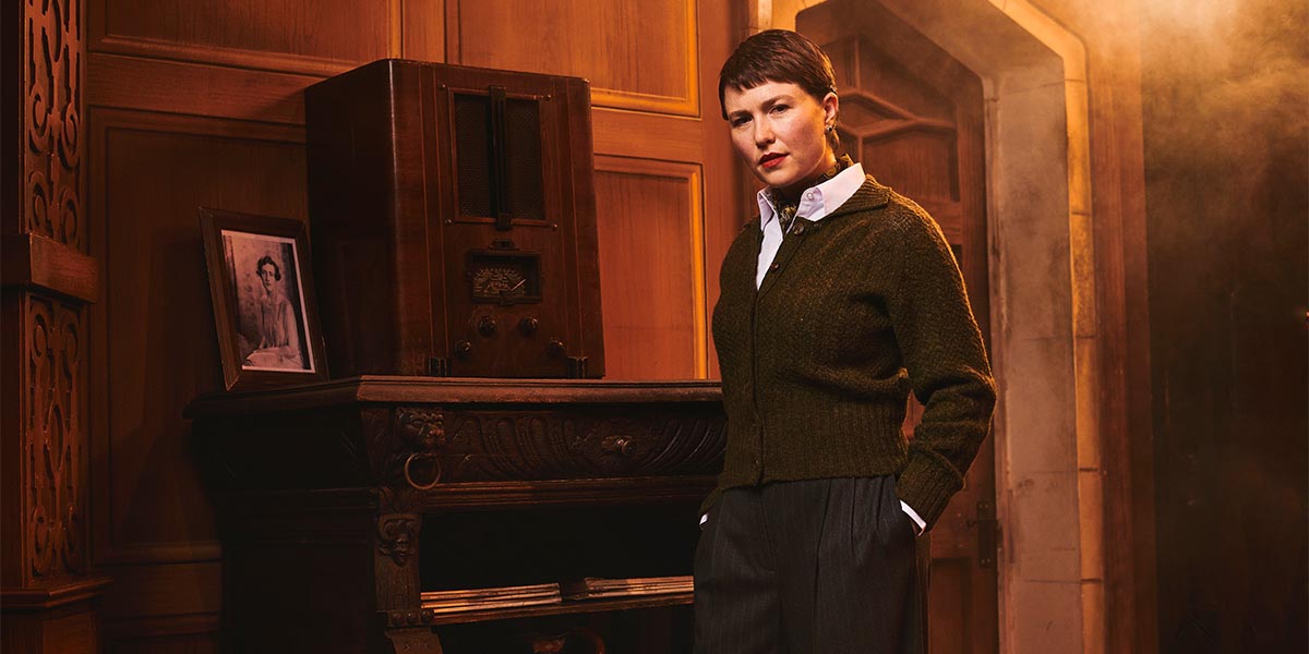 A scene from The Mousetrap featuring actors in period costumes on stage, with dramatic lighting and set design.