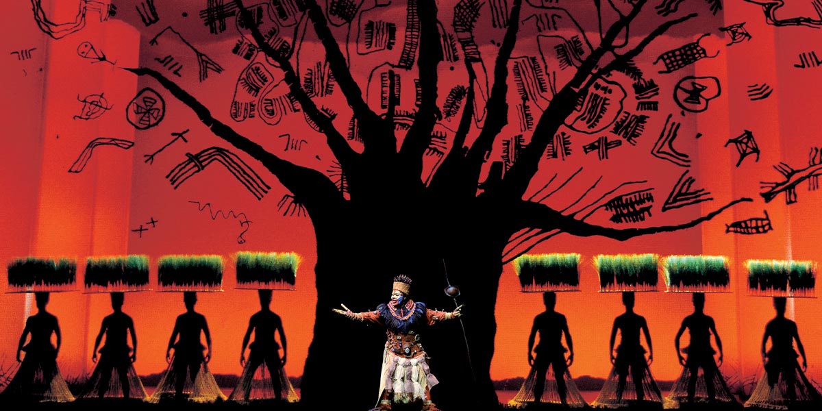 A vibrant tree with intricate branches and leaves, set against a clear blue sky in a natural landscape.