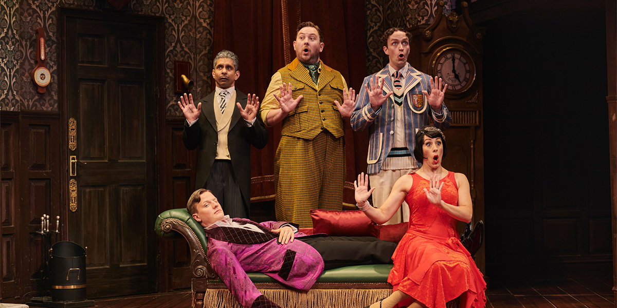 A chaotic scene from "The Play That Goes Wrong," featuring actors in disarray on a cluttered stage.