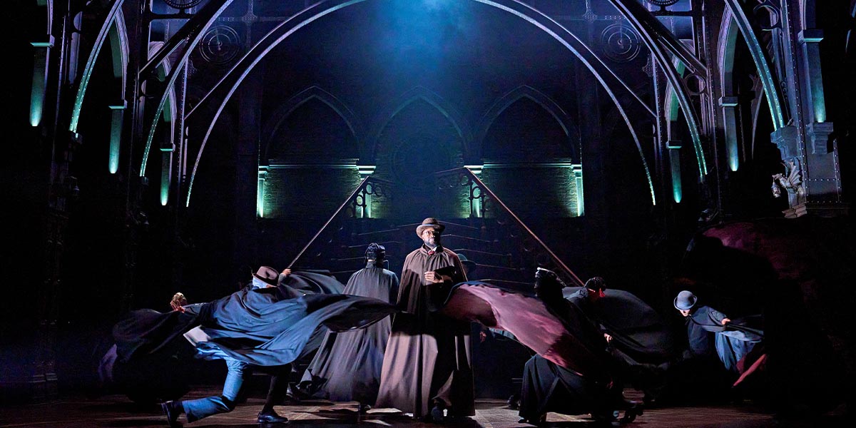 The cast of Harry Potter and the Cursed Child poses together, dressed in theatrical costumes against a dark background.