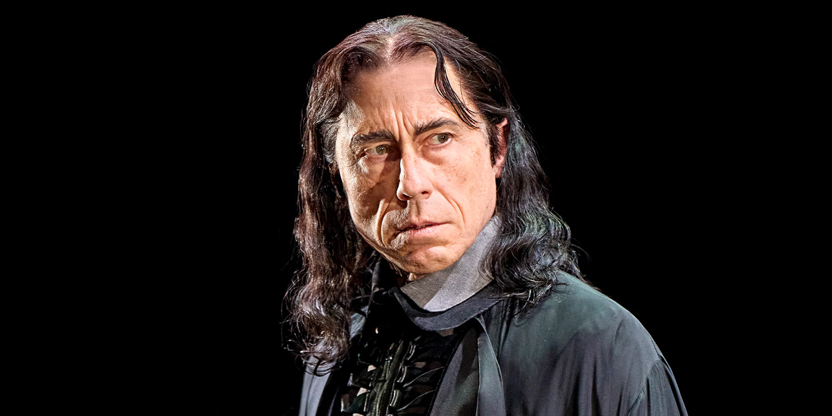 David Annen portrays Severus Snape, with long dark hair and a serious expression against a black background.