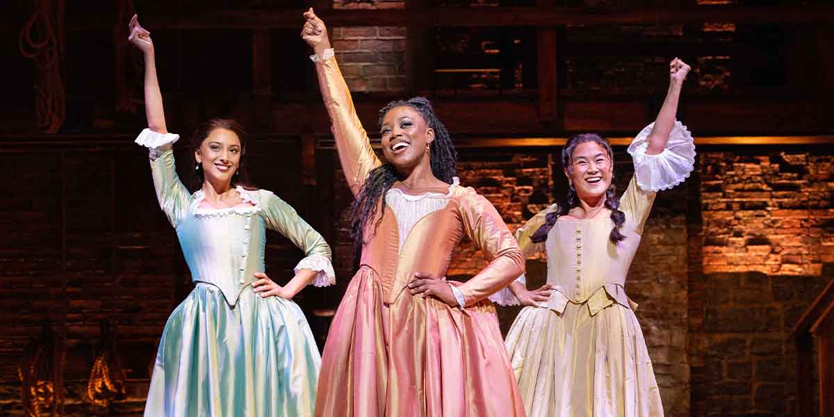 Bente Mulan, Georgina Onuorah, and Jasmine Jia Yung Shen pose joyfully in colourful period costumes.