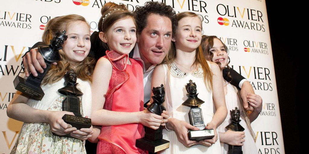 A group of children holding awards poses with a man at the Olivier Awards 2012 event.