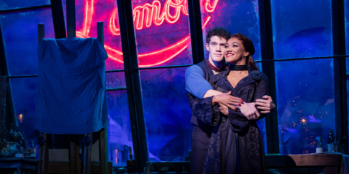 Alistair Brammer and Karis Anderson perform on stage in vibrant costumes from Moulin Rouge! The Musical.