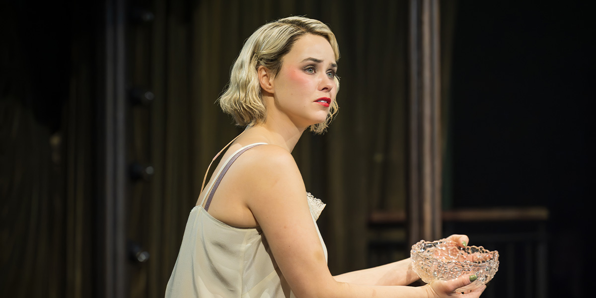 Katie Hall as Sally Bowles, holding a crystal bowl, gazes thoughtfully with a soft expression.