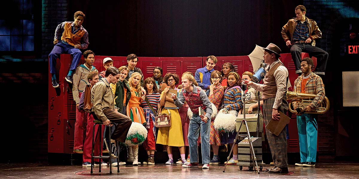 A dramatic scene from "Stranger Things: The First Shadow," featuring characters in dark costumes against a moody backdrop.