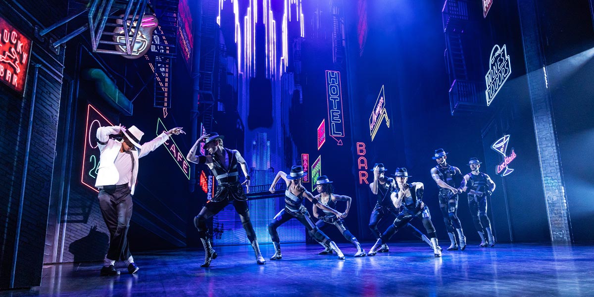 A vibrant stage scene from "MJ The Musical," featuring dancers in dynamic poses and colourful costumes.