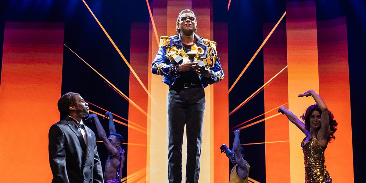 A vibrant stage scene from "MJ The Musical," featuring dancers in dynamic poses with colourful costumes.
