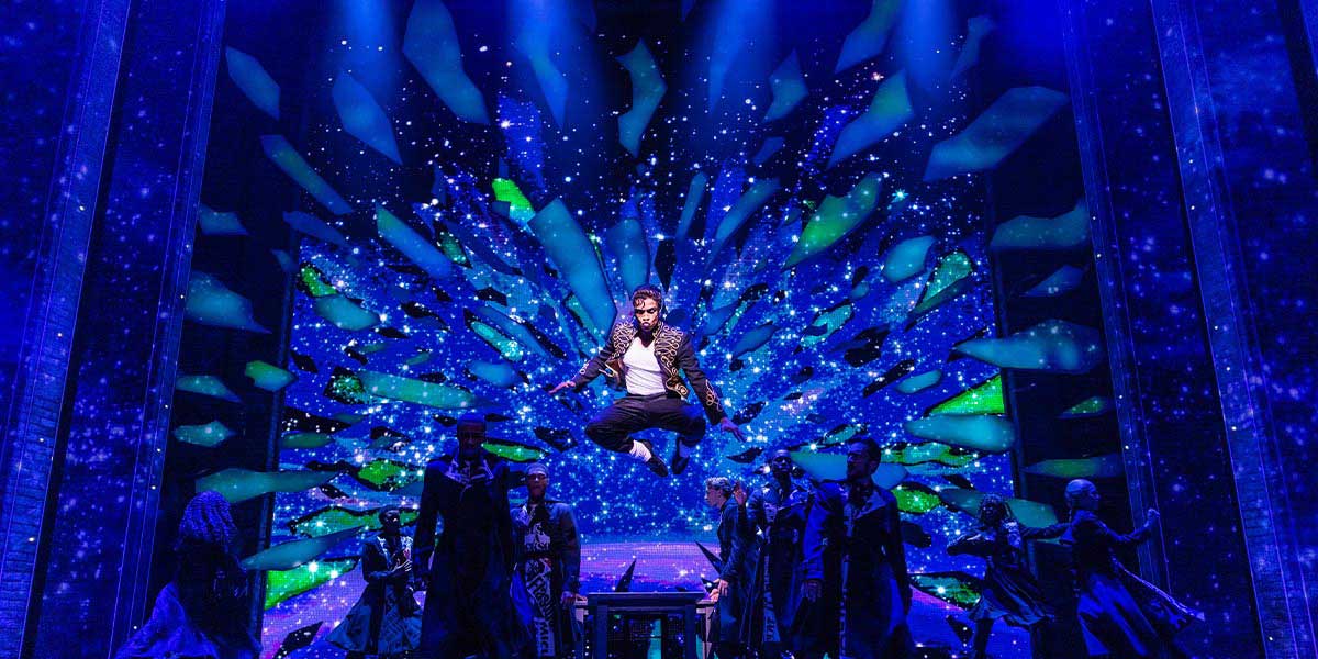 A vibrant stage scene from "MJ The Musical," featuring dancers in dynamic poses and colourful costumes.