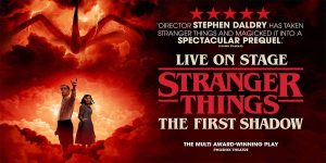A man and woman stand against a dramatic red and black background, promoting "Stranger Things: The First Shadow.