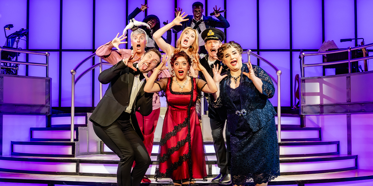A large, ornate ship model displayed on a wooden pedestal, with intricate details and a dark background.