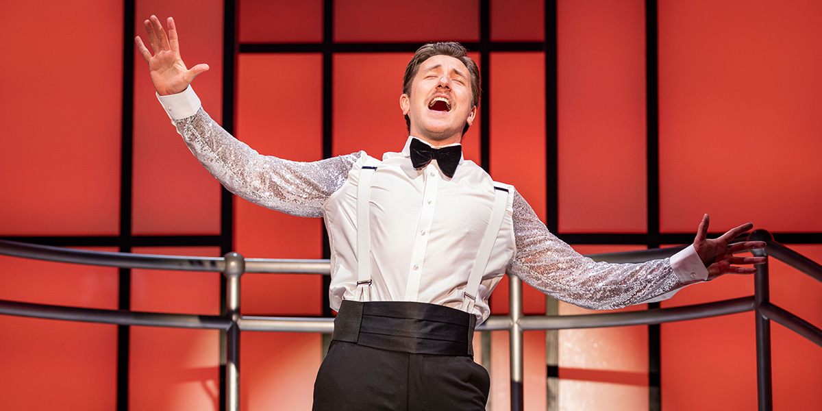 A large shipwreck rests on the ocean floor, surrounded by marine life and sandy seabed.