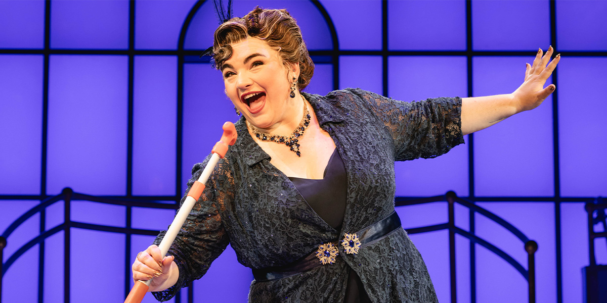 A woman in a flowing white dress stands on a ship's deck, gazing thoughtfully at the ocean.