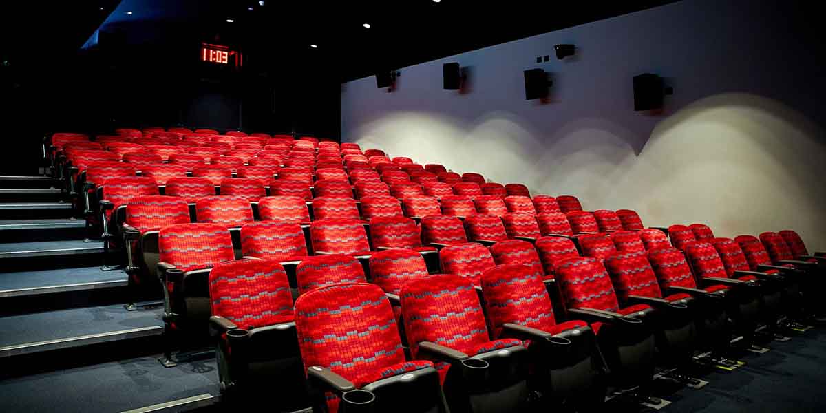 Red upholstered theatre seats arranged in rows, with a digital clock displaying 11:03 in the background.