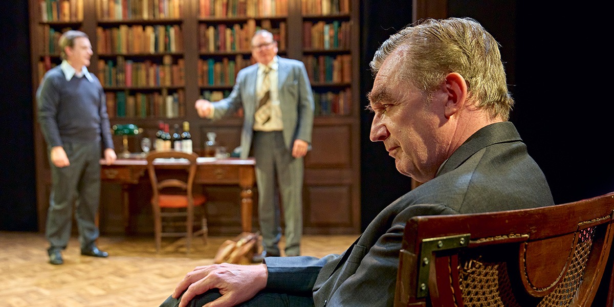 Alan Cox (Tony Crosland) Hywel Morgan (Roy Jenkins ) and Colin Tierney (Denis Healey) are sitting in an office. In the background a large, full bookcase can be seen.