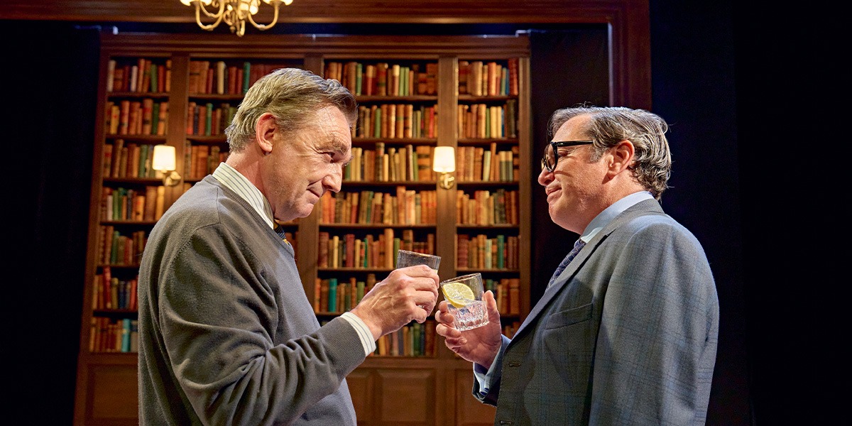 Colin Tierney (Denis Healey) and Hywel Morgan (Roy Jenkins ) are standing together, each holding a glass and holding them together as if to cheers.