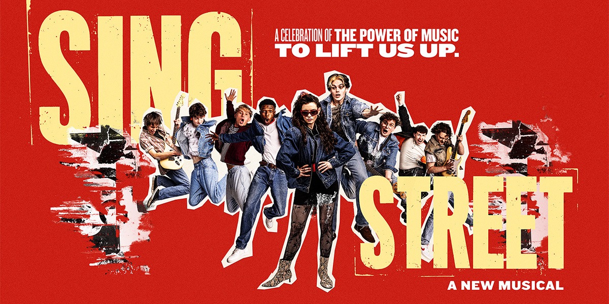 The background is red. In the centre is an image of the company of Sing Street. On the left hand side of this image it reads 'Sing' on the right hand side of this image it reads 'Street' below this it reads 'A new musical'
