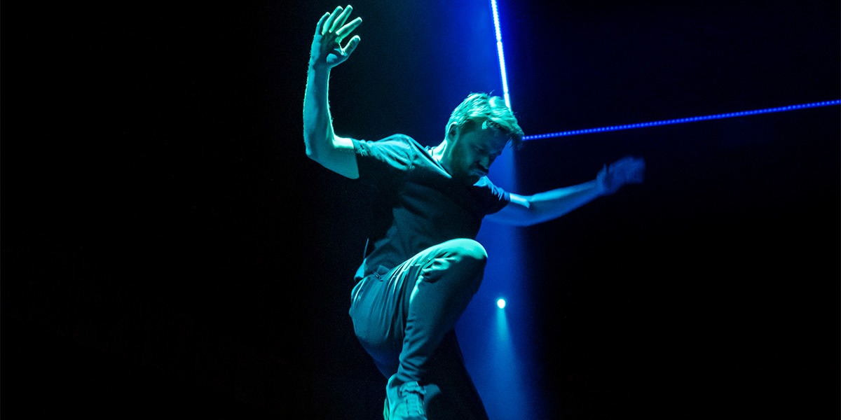 Jack Lowden (Luka) is encompassed in a blue, green light and appears to be jumping.