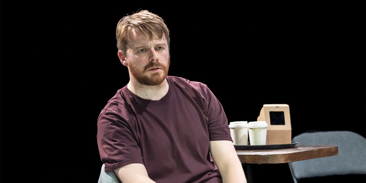 Jack Lowden (Luka) is sitting onstage and appears to be unhappy.