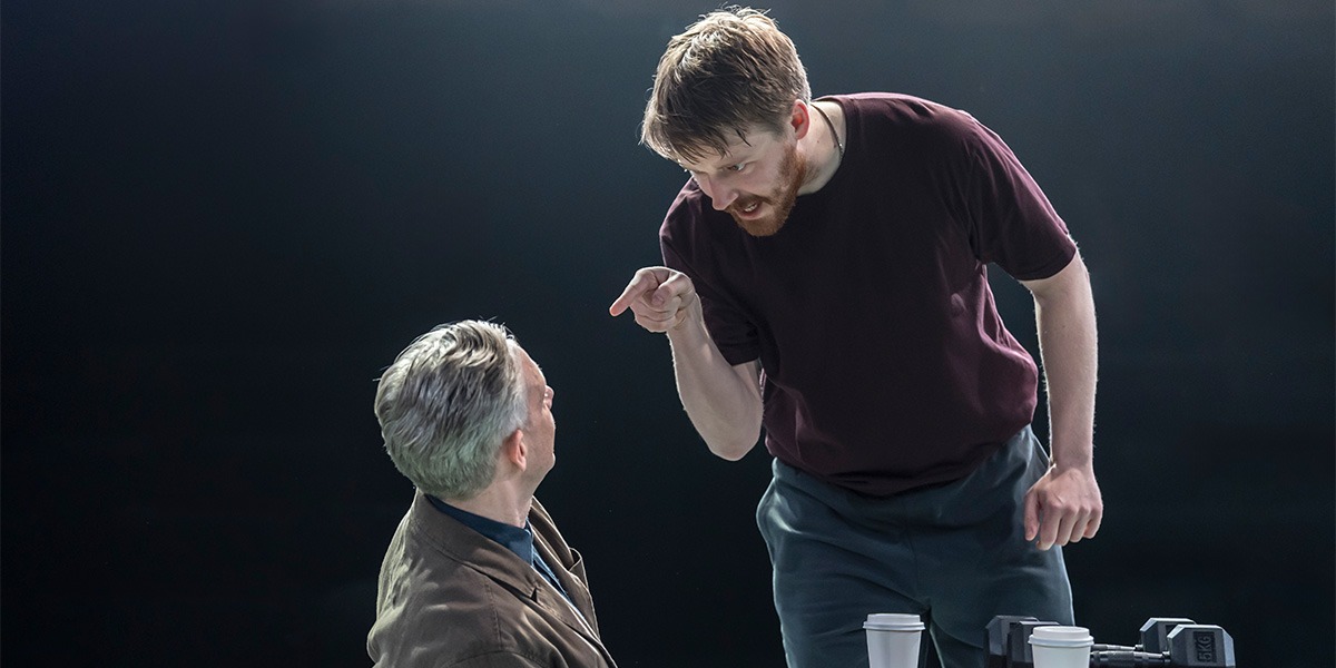 Jack Lowden (Luka) is standing over Martin Freeman (James) appearing angry and pointing down at Martin Freeman (James)