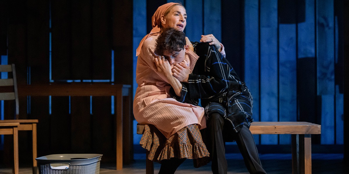 One person has another wrapped in an embrace protectively. Like a mother comforting their child.