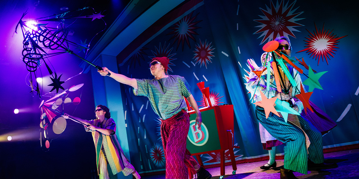 A vibrant stage scene from "The Firework Maker's Daughter," featuring actors in colourful costumes performing.
