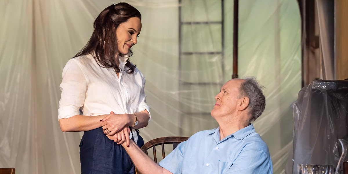 John Lithgow (Roald Dahl) and Rachael Stirling (Felicity Crosland) are holding hands and looking upon one and other smiling.