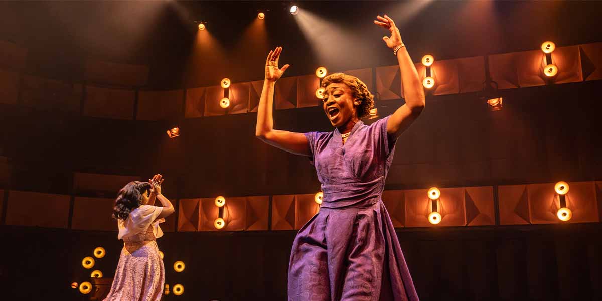 Beverley Knight performs energetically in a purple dress, while Ntombizodwa Ndlovu claps in the background.