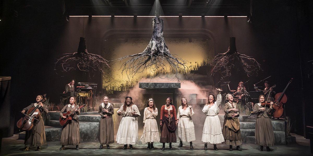 The cast of "Coven" poses together on stage at Kiln Theatre, wearing varied costumes and expressions.