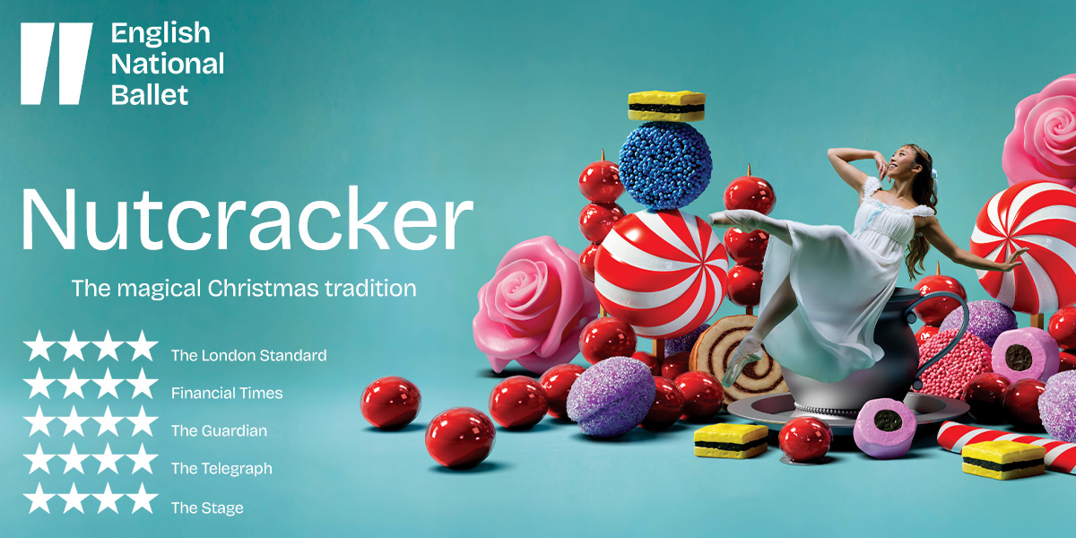 A wooden nutcracker figure in a red and gold uniform stands against a blurred festive background.