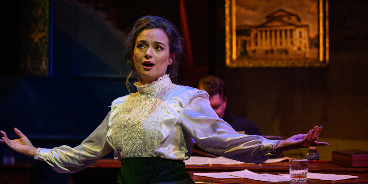 A person performs passionately on stage with expressive hand gestures, dressed in a period costume with a detailed backdrop featuring a classical building.