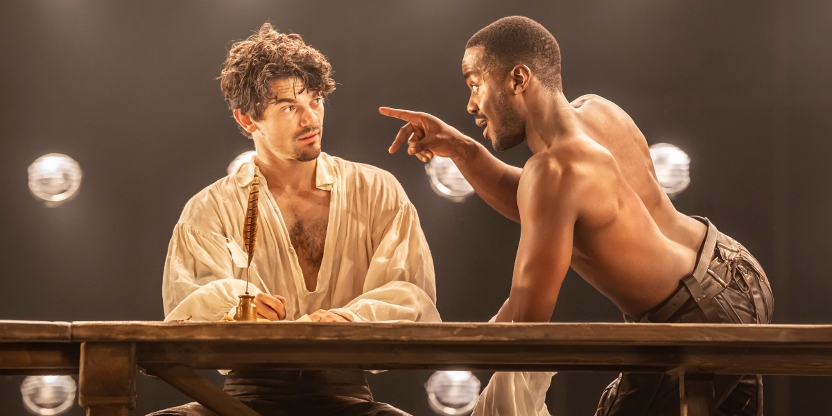 Edward Bleumel and Ncuti Gatwa pose together, smiling, against a blurred outdoor background with greenery.