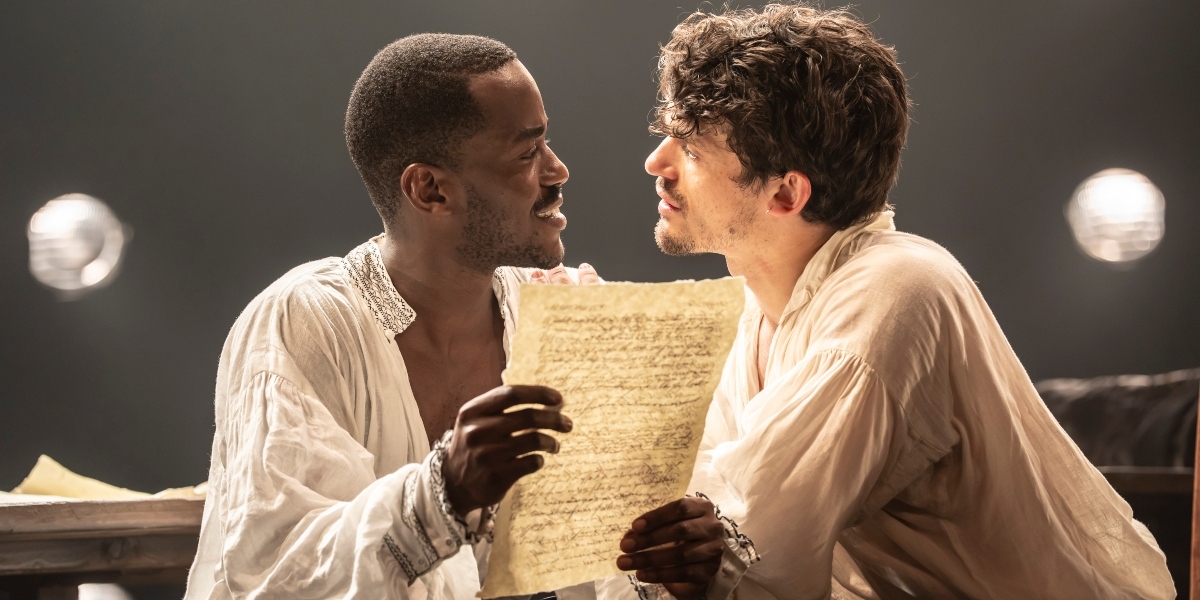 Ncuti Gatwa and Edward Bleumel pose together, smiling, against a soft-focus, neutral background.