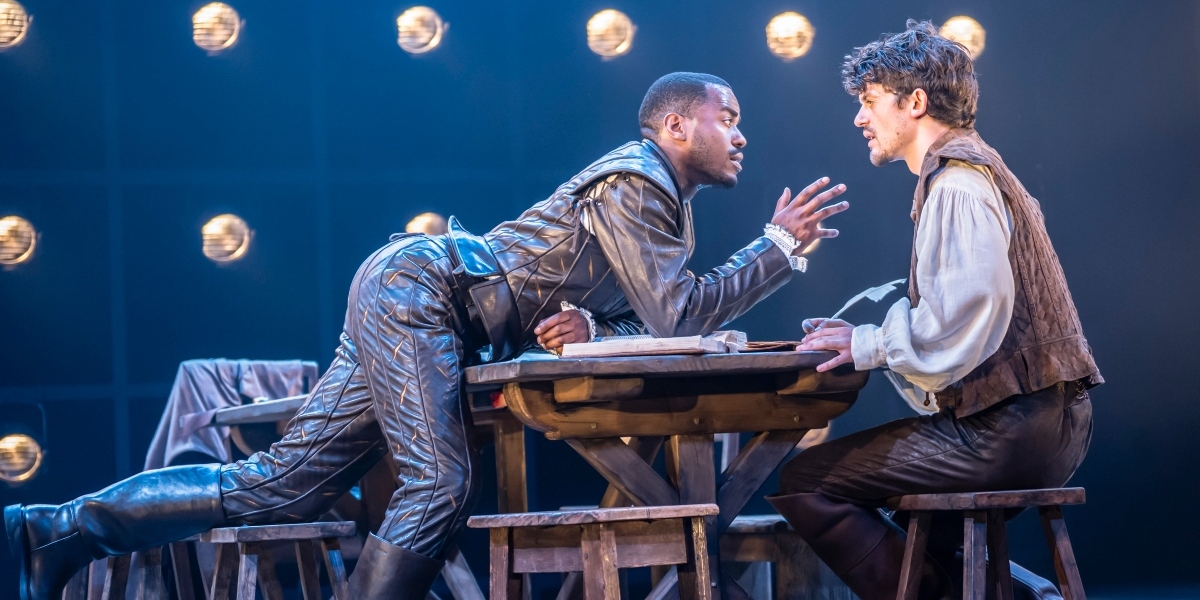 Ncuti Gatwa and Edward Bleumel pose together, smiling, against a soft-focus background with warm lighting.