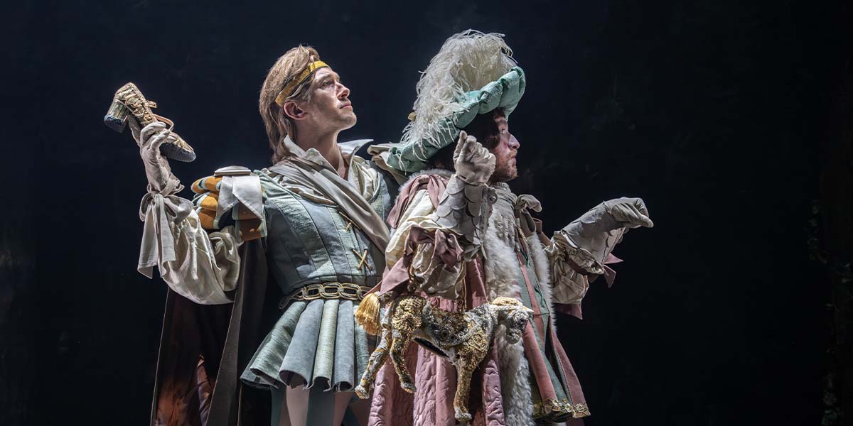 Oliver Savile and Hughie O'Donnell pose together, smiling, in a wooded setting with soft sunlight filtering through trees.