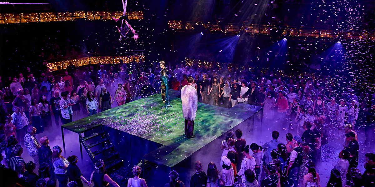 Performers and audience members participate in a vibrant live show featuring colourful lighting and confetti on stage.