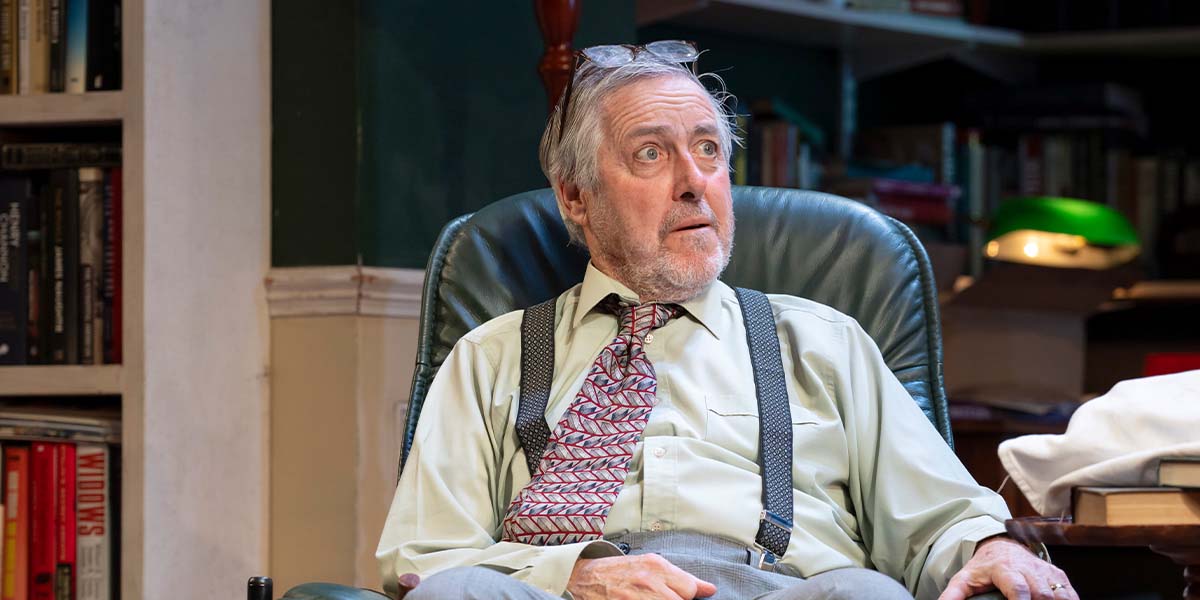 A woman in a blue dress stands at a podium, addressing a crowd with a serious expression.