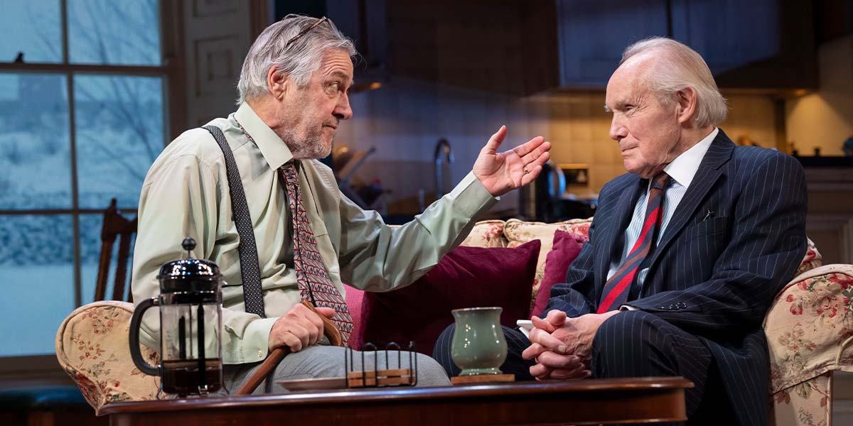 A group of people stands in a formal setting, some holding placards, expressing discontent towards a leader.
