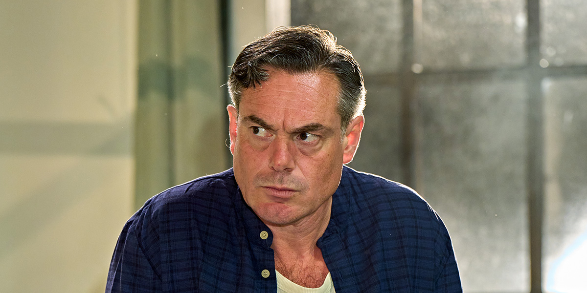 An individual with a concerned expression wearing a dark blue shirt in a room.