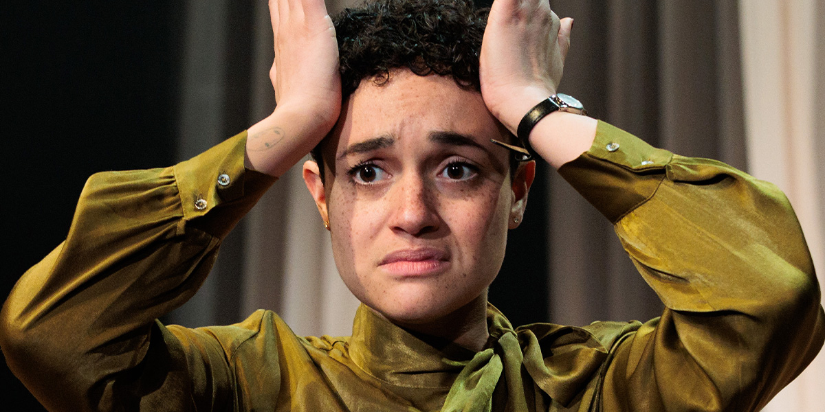 Lily Nichol holds both hands to their head looking upset with a textured background featuring soft colours and subtle patterns.