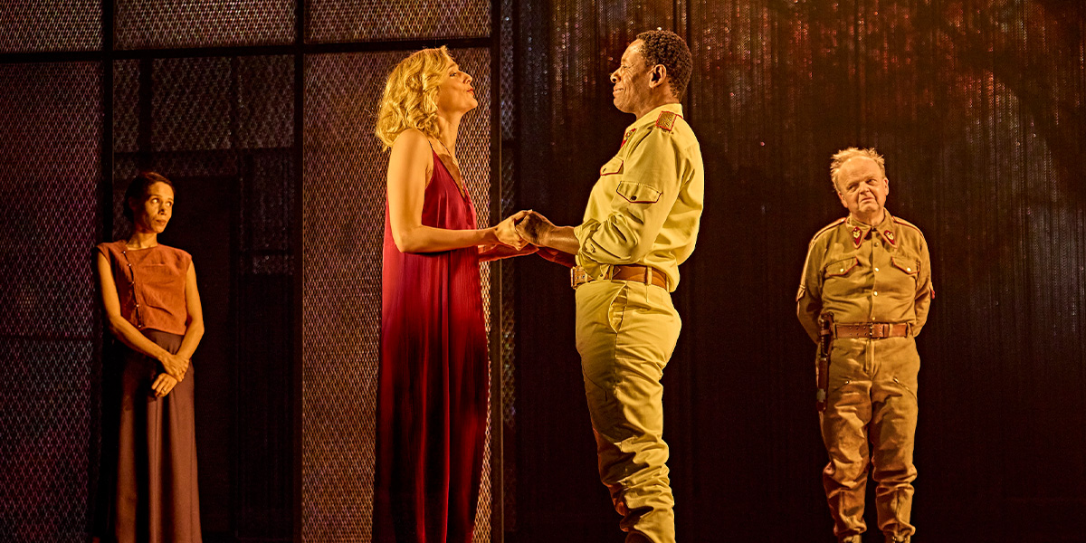 Vinette Robinson as Emilia and David Harewood as Othello hold hands, with Caitlin FitzGerald as Desdemona nearby.