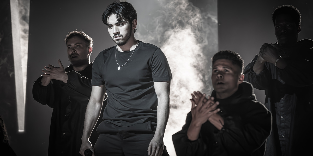 Four individuals standing in a misty room with dramatic lighting.