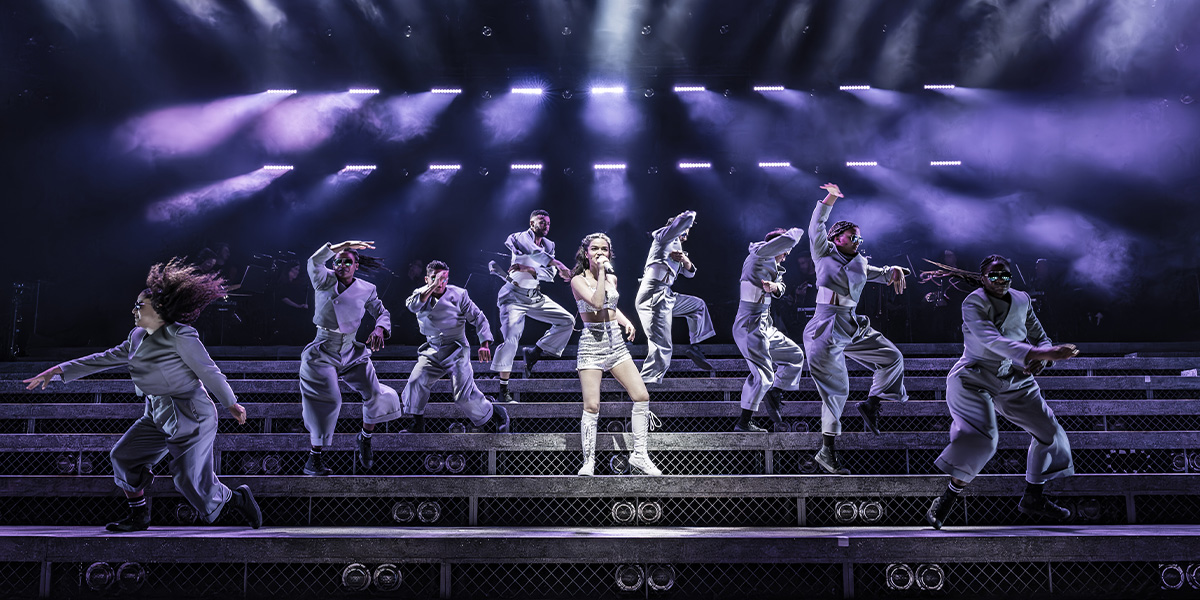 Performers on stage with dynamic lighting and coordinated dance movements