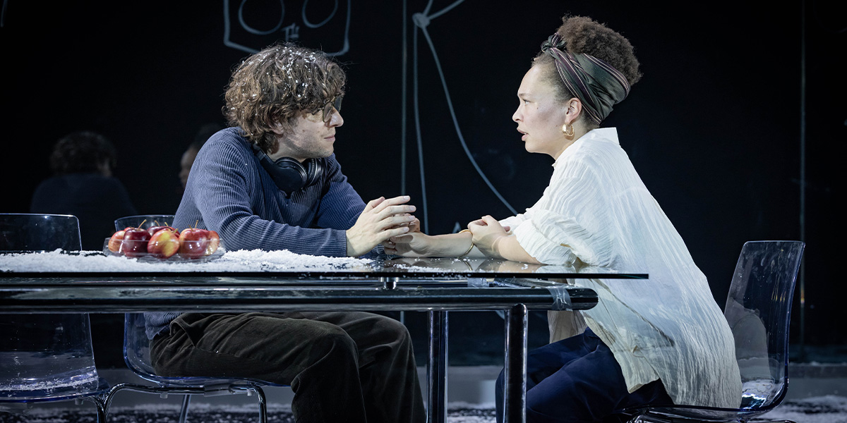 Alexander Forsyth as Abe and Paksie Vernon as Sophie, both in casual clothing, seated together outdoors.