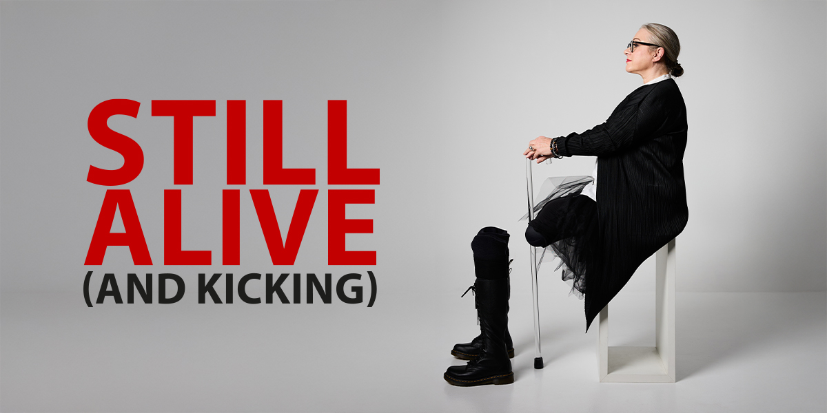 The background is white. On the left it reads 'Still Alive (And Kicking) On the right is an image of a person sitting on a chair.