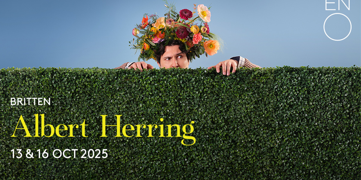 The image shows a person peeping over a green hedge wearing a colourful, head dress made of flowers. At the bottom it reads 'Albert Herring'